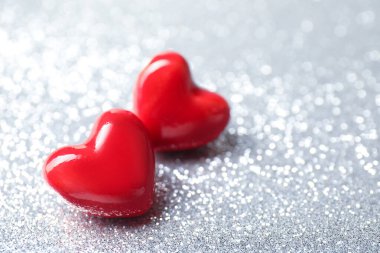 Sevgi. Parlak gri arka planda kırmızı dekoratif kalpler, yakın plan. Metin için boşluk