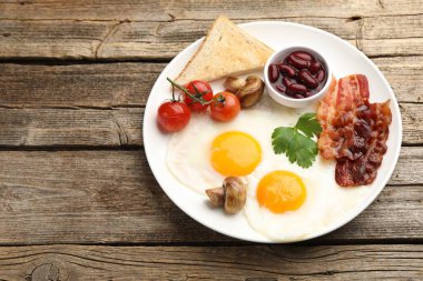 Geleneksel İngiliz kahvaltısı. Pastırmalı, kırmızı fasulyeli, domatesli, mantarlı ve ahşap masada kızarmış ekmekli nefis, güneşli yumurtalar. Metin için boşluk