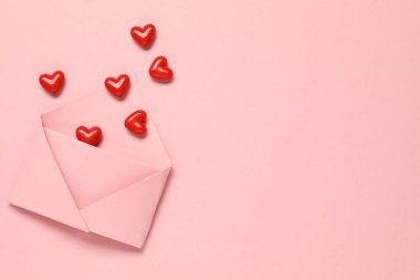 Sevgi. Pembe arka planda kırmızı dekoratif kalpleri olan zarf, düz. Metin için boşluk