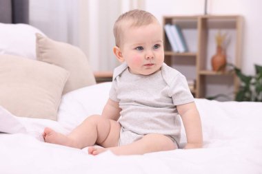 Evdeki yatakta oturan tatlı küçük bebek.