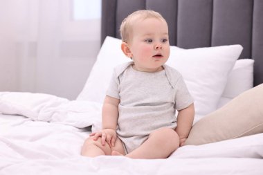Evdeki yatakta oturan tatlı küçük bebek.