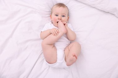 Evdeki yatakta uzanmış şirin küçük bebek, üst manzara.