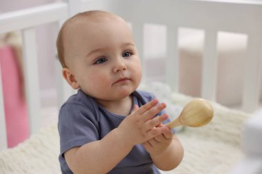 Evdeki beşiğinde ahşap çıngıraklı şirin bebek, yakın plan.