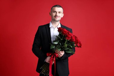 Sevgililer Günü kutlaması. Kırmızı arka planda güzel gül buketi olan adam.