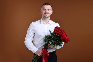 Sevgililer Günü kutlaması. Kahverengi arka planda kırmızı gül buketi olan bir adam.
