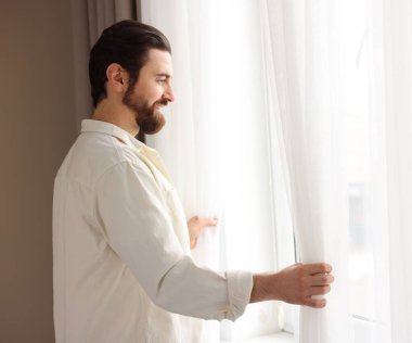 Evde şık pencere perdeleri açan adam