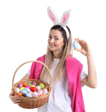 Paskalya kutlaması. Saç bandı takmış, tavşan kulaklı, hasırdan sepet dolusu beyaz arka planda boyalı yumurtaları olan gülümseyen bir kadın.