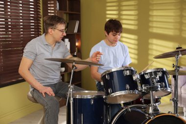 Genç çocuk içeride müzik öğretmeniyle bateri çalmayı öğreniyor.