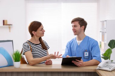 Klinikteki resepsiyonda hastaya yardım eden tıbbi asistan