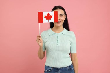 Pembe arka planda Kanada bayrağı taşıyan mutlu kadın.