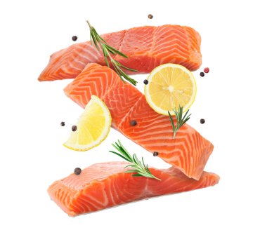 Beyaz arka plana düşen biberiye ve limonlu taze somon parçaları.