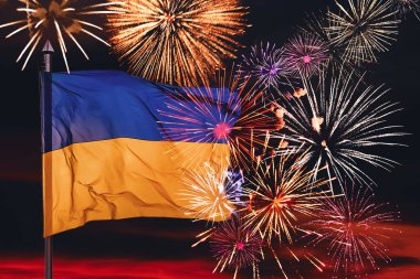 Ukrayna bayrağı ve gece gökyüzünde parlak havai fişekler. Ulusal bayram kutlaması