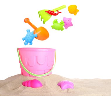 Çocuklar için plaj oyuncakları. Plastik kalıplar ve araçlar beyaz arkaplana karşı kum üzerinde kovaya düşebilir