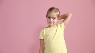 Renkli saç eklentileri olan küçük bir kız pembe arka planda baş parmak gösteriyor. Metin için boşluk