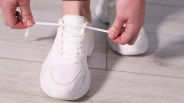 Beyaz spor ayakkabı bağcığı bağlayan kadın, yakın plan. Kamera yukarı hareket ediyor