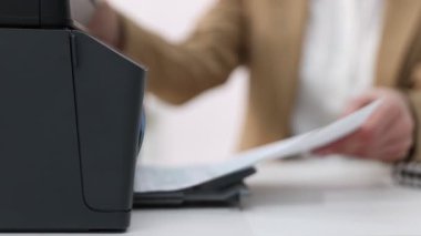 Beyaz masadaki yazıcıdan baskı kağıdı alan kadın, seçici odaklı.