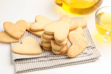 Lezzetli kalp şeklinde tereyağlı kurabiye ve çay beyaz masada, yakın plan.