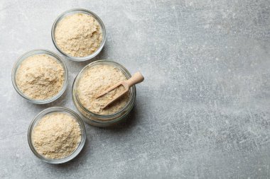 Kaselerdeki kuru maya taneleri, gri masada kavanoz ve kepçe, düz uzanma. Metin için boşluk