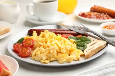 Lezzetli bir kahvaltı. Sosis ve domatesli nefis çırpılmış yumurta. Masada servis ediliyor. Yakın plan.