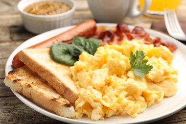 Lezzetli bir kahvaltı. Pastırmalı yumurta ve sosis. Masada servis ediliyor. Yakın plan.