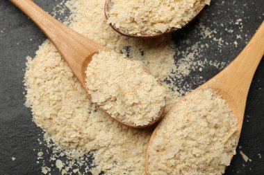 Tahta kaşıklardaki kuru maya taneleri siyah masada, düz yatıyordu.