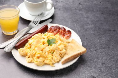 Lezzetli bir kahvaltı. Pastırmalı, sosisli ve ekmekli leziz omlet. Gri desenli masada servis ediliyor. Yakın plan. Metin için boşluk