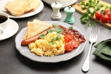 Lezzetli bir kahvaltı. Pastırmalı, sosisli ve domatesli leziz omlet. Gri desenli masada servis ediliyor. Yakın plan.