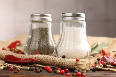 Ahşap masada baharatlı tuzluk ve biberlikler, yakın plan.