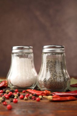 Ahşap masada baharatlı tuzluk ve biberlikler, yakın plan.