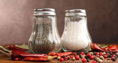 Ahşap masada baharatlı tuzluk ve biberlikler, yakın plan.