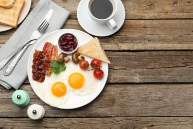 Geleneksel İngiliz kahvaltısı. Pastırmalı, fasulyeli, domatesli, mantarlı ve ahşap masada servis edilen kızarmış ekmekli nefis, güneşli yumurtalar. Metin için boşluk