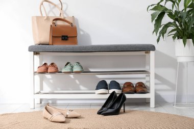 Farklı ayakkabılar, aksesuarlar ve beyaz duvarın yanındaki ev bitkilerinden oluşan ayakkabı deposu.