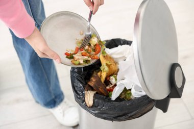 Mutfaktaki çöp tenekesine yemek atan kadın, yakın plan.