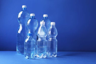 Mavi arka planda farklı boyutlarda su şişeleri var. Metin için boşluk