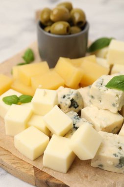 Açık mermer masada değişik peynir, zeytin ve fesleğen içeren servis panosu, yakın plan.