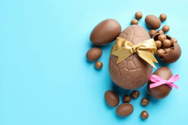 Çikolatalı Paskalya yumurtaları, şekerli ve fiyonklu açık mavi arka plan, düz. Metin için boşluk