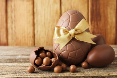 Mutlu Paskalyalar. Ahşap masada şekerli çikolatalı yumurtalar, yakın plan. Metin için boşluk