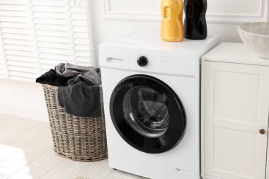 Çamaşır sepetinde çamaşır makinesinin yanında kirli çamaşırlar.