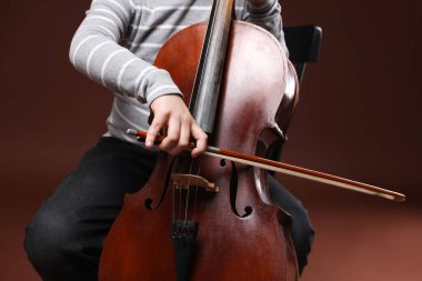 Kahverengi arka planda keman çalan sevimli küçük çocuk, yakın plan.