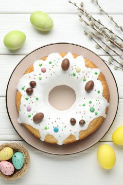 Lezzetli Paskalya pastası, boyanmış yumurtalar ve söğüt dalları beyaz ahşap masa üzerinde, düz uzanmış