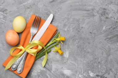 Paskalya sofrası. Gri desenli arka planda nergisleri olan güzel gümüş takımlar, üst manzara. Metin için boşluk