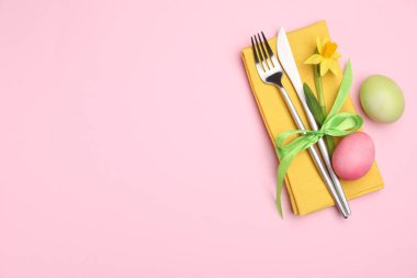 Paskalya sofrası. Nergis çiçekli güzel gümüş eşyalar ve pembe arka planda boyanmış yumurtalar, üst manzara. Metin için boşluk