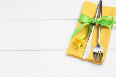 Paskalya sofrası. Beyaz ahşap zemin üzerinde nergis çiçeği olan güzel gümüş eşyalar, üst manzara. Metin için boşluk