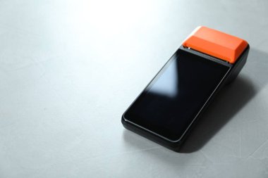 Açık gri masada bir ödeme terminali, yakın plan. Metin için boşluk