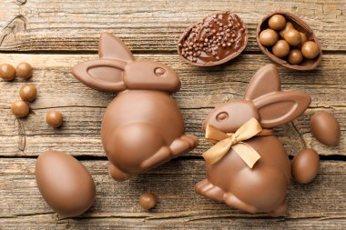 Çikolatalı Paskalya tavşanları ve yumurtalar ahşap masada, düz yatıyordu.