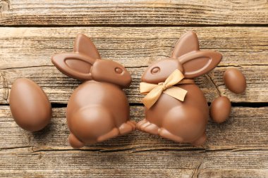 Çikolatalı Paskalya tavşanları ve yumurtalar ahşap masada, düz yatıyordu.