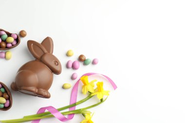 Çikolatalı Paskalya tavşanı, çiçekler, beyaz arka planda kurdele ve yumurtalar, düz yatak. Metin için boşluk