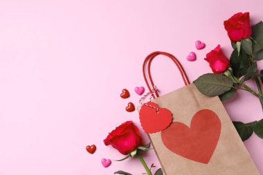 Kese kağıdı, güller ve pembe arka planda dekoratif kalpler. Metin için boşluk