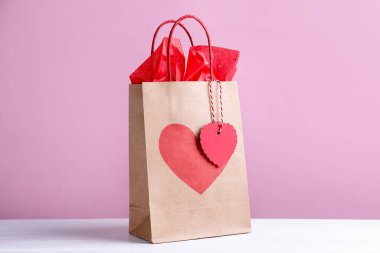 Pembe arka planda kalbi beyaz masada olan hediye paketi. Sevgililer Günü