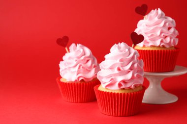 Sevgililer Günün kutlu olsun. Kırmızı arka planda kalp kapakları olan lezzetli kekler, yakın plan. Metin için boşluk